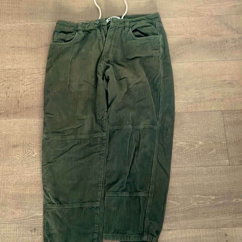 Green corduroy pants with drawstrings, belt loops, and baggy fit.
